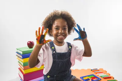 Smiling child showing painted hands at school